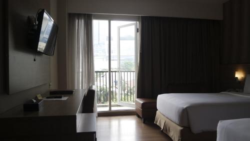 ジャカルタにあるアヤカ スイーツのベッド1台、窓、バルコニーが備わるホテルルームです。