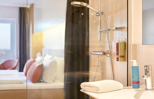 ducha con puerta de cristal junto a un baño en Strandgut Resort, en Sankt Peter-Ording