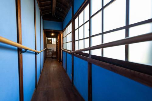 a hallway of a building with blue walls and windows at Hostel 東風ノ家（Kochi-no-ya） in Aki