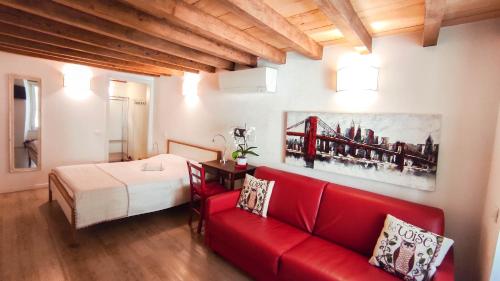 salon z czerwoną kanapą i łóżkiem w obiekcie B&B ai Musei w mieście Brescia