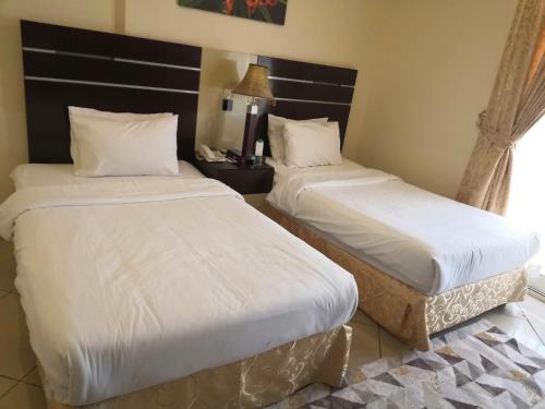 2 bedden in een hotelkamer met witte lakens bij Boulevard City Suites Hotel Apartments in Dubai