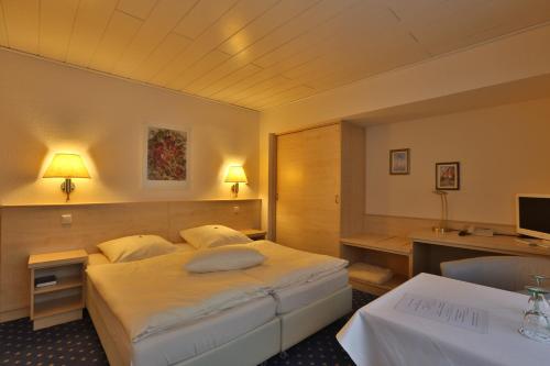 シュタットハーゲンにあるParkhotel Stadthagenのベッドとデスクが備わるホテルルームです。