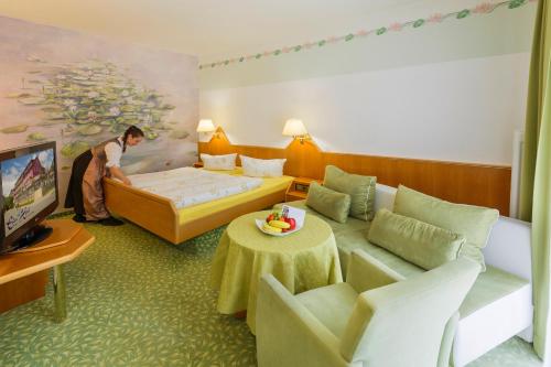 a man in a hotel room with a bed and a tv at Eden Hotel in Bad Krozingen