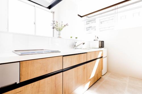 Una cocina con gabinetes de madera y un fregadero. en TOGOSHI 568 STAY Togoshi Ginza, en Tokio