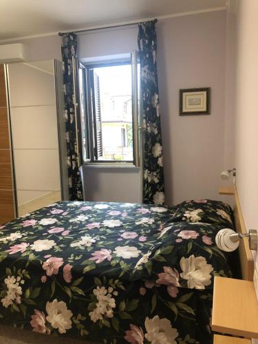 a bedroom with a bed with a floral bedspread and a window at B&B Antonella in Monterotondo