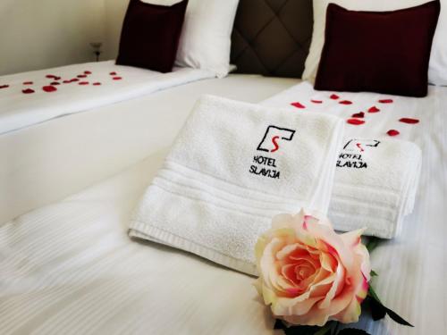 a hotel room with two beds with towels and a rose at Hotel Slavija Banja Luka in Banja Luka