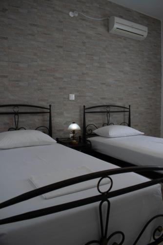 two twin beds in a room with a brick wall at Kouki Maria Rooms in Apollonia