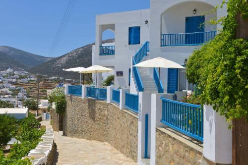 - un bâtiment bleu et blanc avec des escaliers et des parasols bleus dans l'établissement Kouki Maria Rooms, à Apollonia
