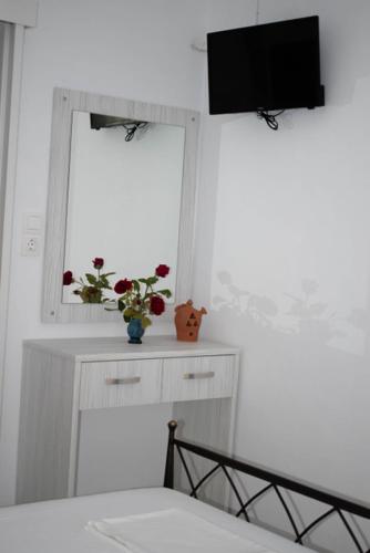 a bedroom with a television and a window with flowers at Kouki Maria Rooms in Apollonia