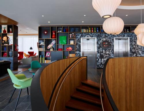 a lobby with a staircase and green chairs at citizenM London Shoreditch in London
