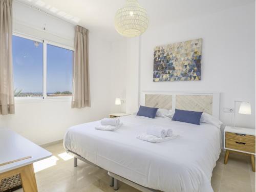 een witte slaapkamer met een groot wit bed met blauwe kussens bij 2308- 2bedrooms apt with stunning sea view-terrace in Manilva