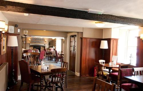 a restaurant with tables and chairs and a woman in the background at Woolpack Inn by Greene King Inns in Frome