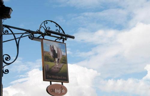a sign hanging from a pole on a street at Woolpack Inn by Greene King Inns in Frome