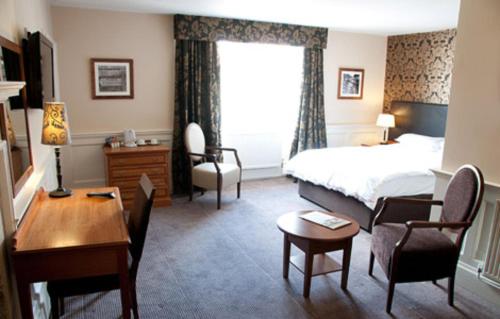 a hotel room with a bed and a desk and a table at Woolpack Inn by Greene King Inns in Frome