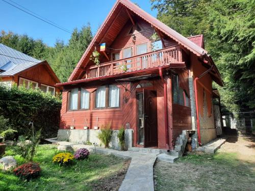 a wooden house with a porch and a balcony at Casuta Paterau Cheia, Prahova in Cheia
