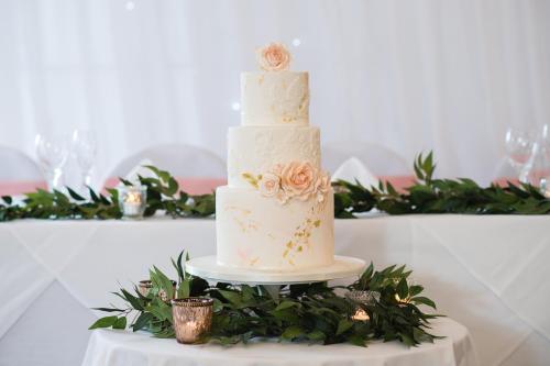 a three tiered wedding cake with flowers on a table at Lakeside Park Hotel & Spa in Ryde