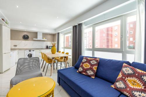een woonkamer met een blauwe bank en een tafel bij Lujan Deluxe Suites by Valcambre in Sevilla