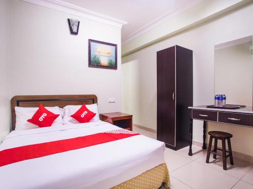 een slaapkamer met een bed met rode kussens en een bureau bij Super OYO 89363 Casavilla Hotel in Batu-grotten