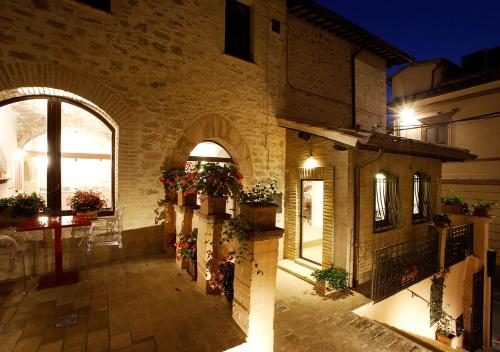 a building with potted plants in a courtyard at night at Hotel Sorella Luna in Assisi