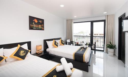 a hotel room with two beds and a balcony at Hoang Long Hotel Phan Thiết in Phan Thiet