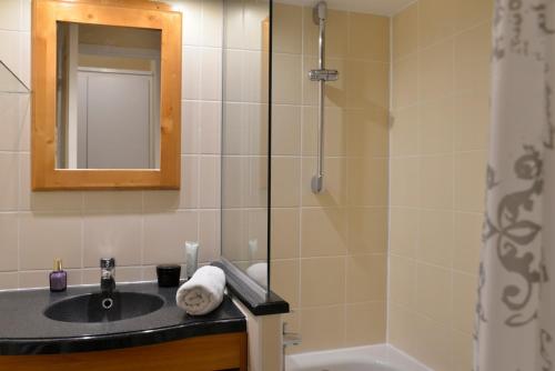 une salle de bain avec un lavabo et une douche avec un miroir dans l'établissement travelski home select - Résidence Licorne, à La Plagne