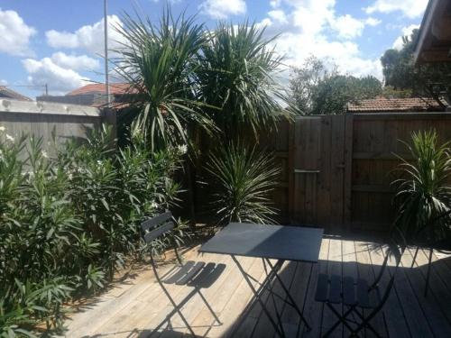 d'une terrasse avec une table et un banc dans une cour. dans l'établissement La cabane poetique, à La Teste-de-Buch