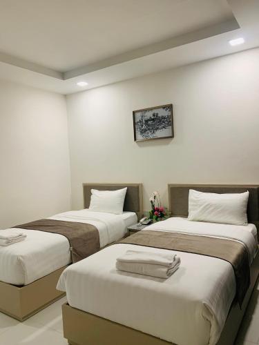 two beds in a room with white walls at Icare Residence & Hotel in Bangkok