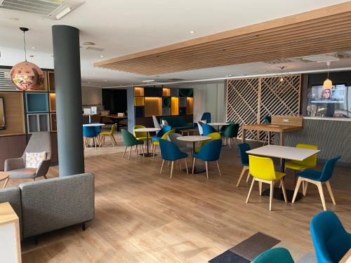 a restaurant with tables and chairs in a room at Holiday Inn Sittingbourne by IHG in Sittingbourne