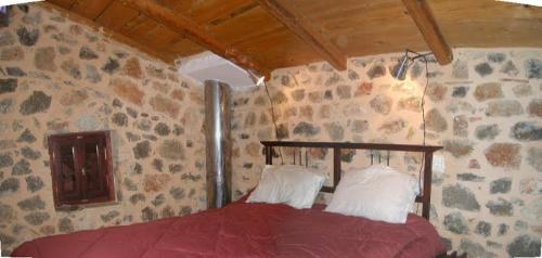 a bedroom with a red bed in a stone wall at ΕΥμορφο σαν παραμύθι ΑΜΥΓΔΑΛΙΑ in Amfiklia