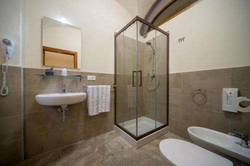 a bathroom with a shower, sink, and toilet at Chiostro Delle Monache Hostel Volterra in Volterra