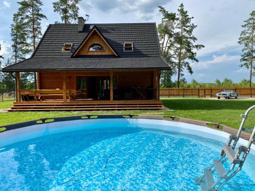 una casa con piscina frente a una casa en Całoroczne domy z bala - CASA DEL CZYŻYK, en Serwy