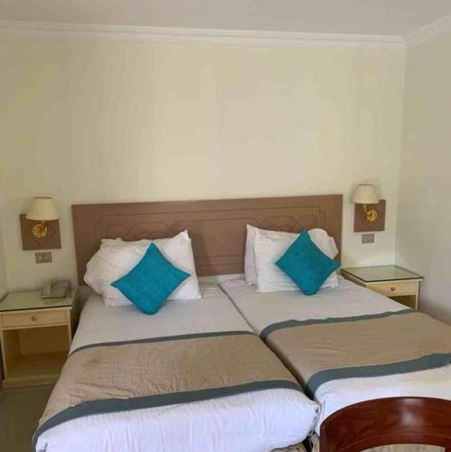 two beds in a hotel room with blue pillows at Cairo Pyramids Hotel in Cairo