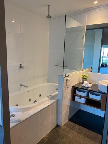a white bathroom with a tub and a sink at Dolphin View 404 in Mandurah