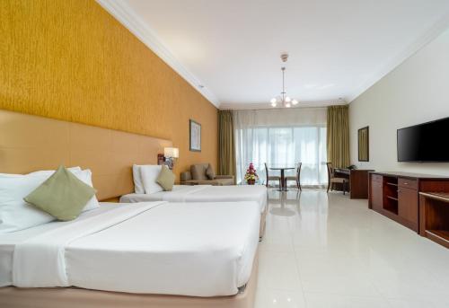 a hotel room with two beds and a flat screen tv at Star Metro Deira Hotel Apartments in Dubai