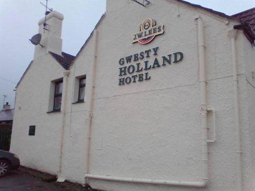 a white building with a sign on the side of it at Holland Hotel in Llanfachraeth