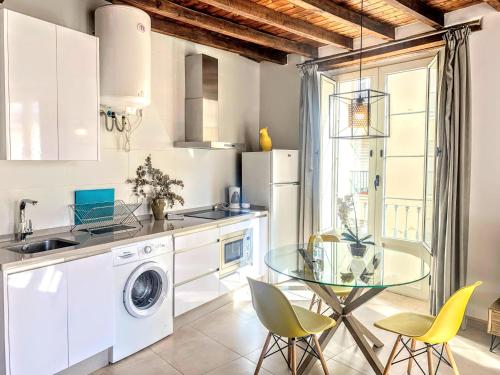 マラガにあるHomely Málaga Loft Gaona Centroのガラステーブルと黄色の椅子付きのキッチン