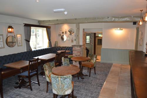 a restaurant with tables and chairs and a couch at The Forresters Arms Kilburn in Kilburn