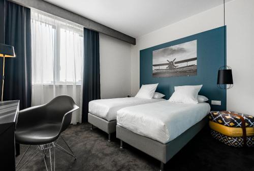 ein Hotelzimmer mit 2 Betten und einem Stuhl in der Unterkunft Najeti Hôtel Lille Nord in Bondues