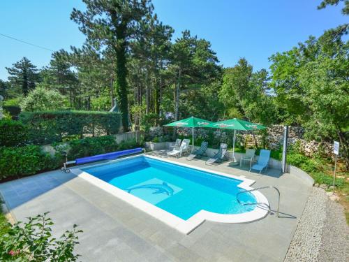 a swimming pool with chairs and umbrellas in a yard at Apartment Fuma-3 by Interhome in Jadranovo