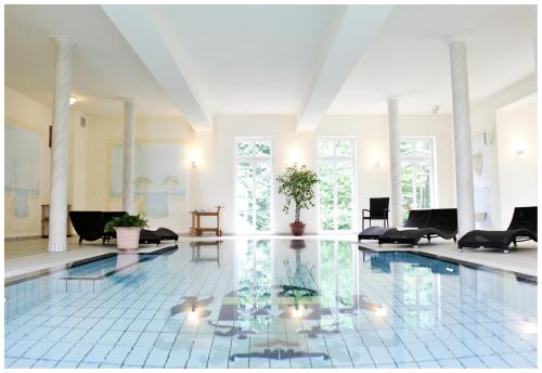 a large swimming pool in a room with chairs and tables at Seeschloss Schorssow in Schorssow