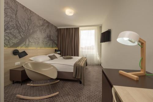 リュブリャナにあるB&B Hotel Ljubljana Parkのベッドと椅子付きのホテルルーム