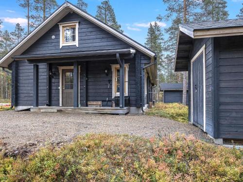 a black house with a gravel driveway in front of it at Holiday Home Honkahovi by Interhome in Ylläsjärvi