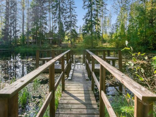 un pont en bois sur un étang dans une forêt dans l'établissement Holiday Home Viinakorpi by Interhome, à Somerniemi