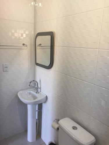 a bathroom with a sink and a toilet and a mirror at Paraíso do Rosa in Praia do Rosa