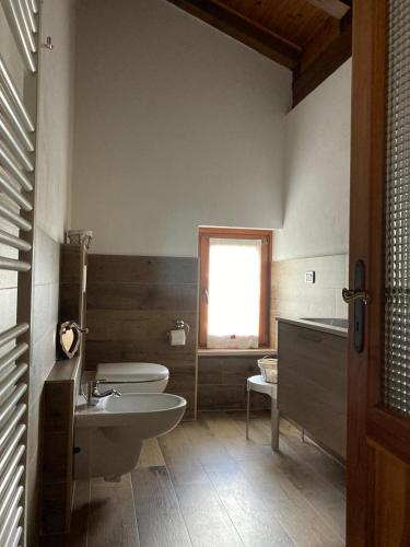 a bathroom with a sink and a toilet and a window at mansarda La Ruine in Morgex