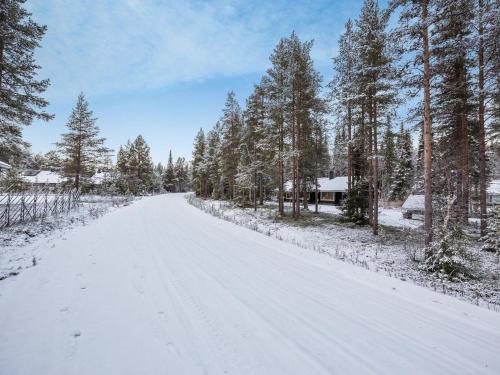 une route enneigée avec des arbres et une maison dans l'établissement Holiday Home Harpan maja-mesimarja by Interhome, à Äkäslompolo
