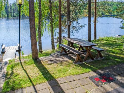 a wooden picnic table sitting next to a lake at Holiday Home Aurinkoranta by Interhome in Hattusaari
