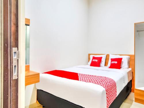 een slaapkamer met een wit bed met rode kussens bij OYO 3346 Rukos Colombus G5 in Telukjambe
