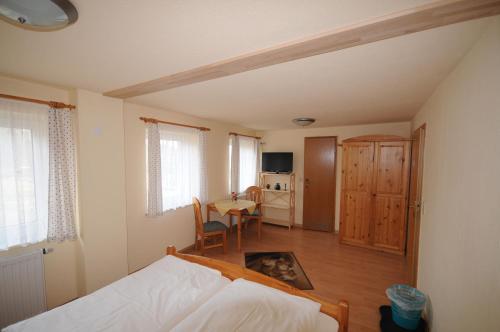a bedroom with a bed and a table and a kitchen at Pension Klette in Kurort Oybin