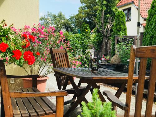 a wooden table and chairs with flowers on a patio at Spreewaldapartments-Kossatz in Lübben